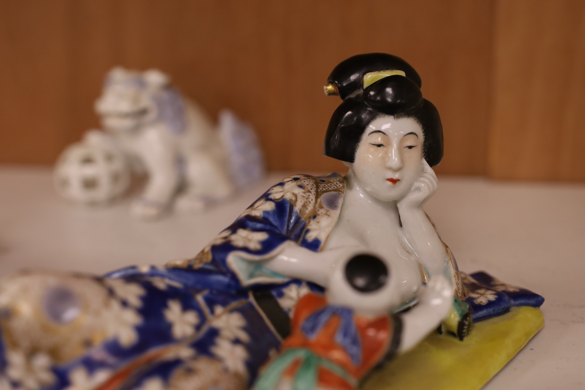 A Japanese enamelled reclining figure of mother and baby and two Hirado style shi-shi figures, reclining figure group 21cm wide. Condition - good